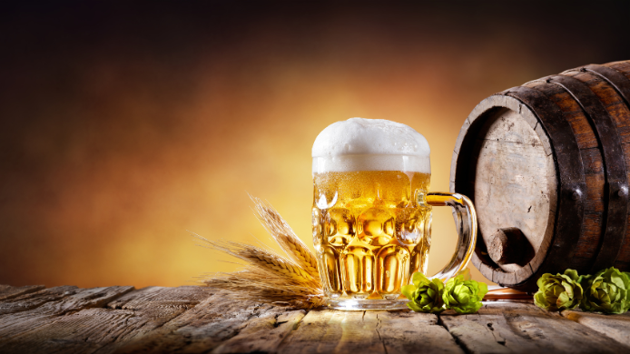 Cerveza rubia junto a barril de madera y lúpulo
